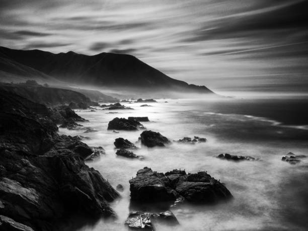 Morning mist surrounds the foot of the mountain. Huge waves crashed against the rocks.