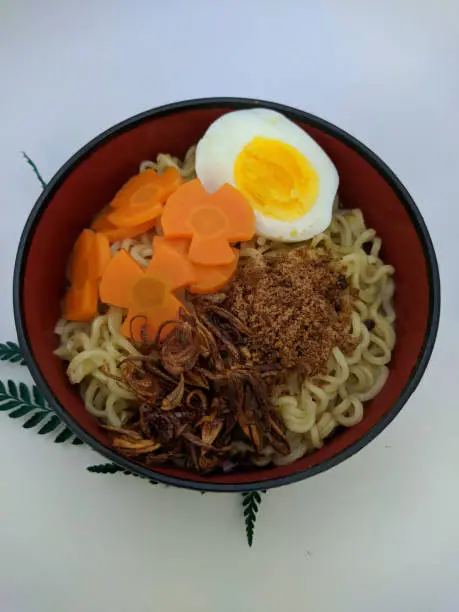 Photo of a bowl of noodles with some decorations on a white background