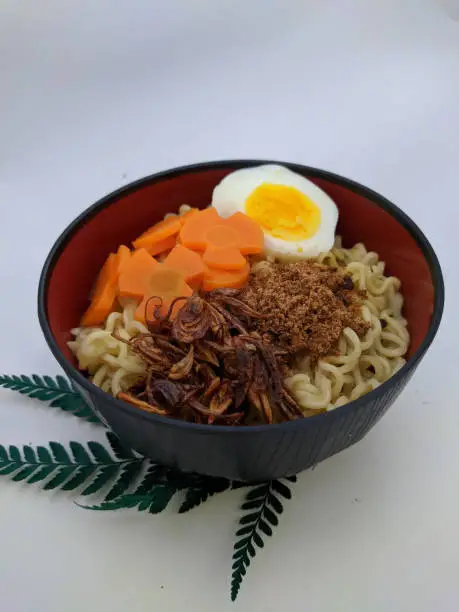 Photo of the noodles are in a black bowl with a white background