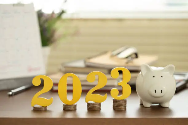 Photo of Word 2023 put on coins stacked with a piggy bank on the desk. Money, Budget, tax, investment, financial, savings, and New Year Resolution concepts. goals and plans for next year.