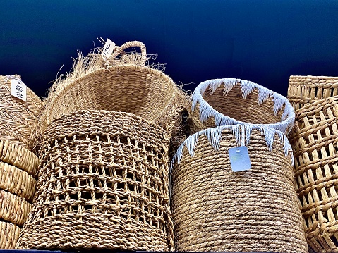 Horizontal still life of stack of handmade fair trade woven wicker artisan market baskets against black wall