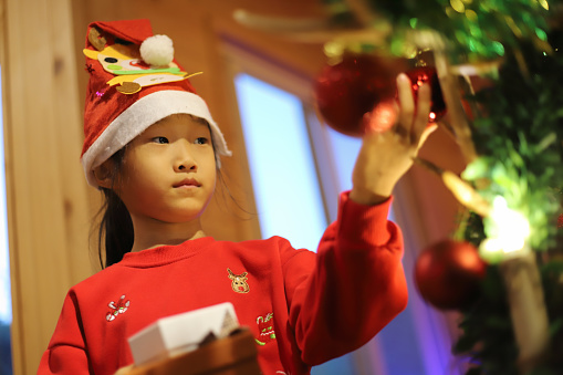 a Asian girl wearing homemade santa hat and christmas tree