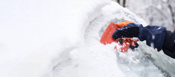 istock Man cleans his car after a snowfall. Cleaning snow from windshield, Scraping ice, Winter car window cleaning 1446608047