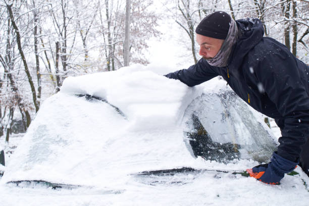 istock Man cleans his car after a snowfall. Cleaning snow from windshield, Scraping ice, Winter car window cleaning 1446608049