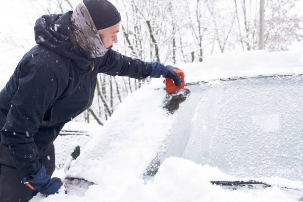 istock Man cleans his car after a snowfall. Cleaning snow from windshield, Scraping ice, Winter car window cleaning 1446608050