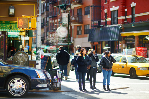 New York - March  16, 2015: People crossing a street in downtown Manhattan. Tourists and new yorkers walking across a busy NYC crosswalk.