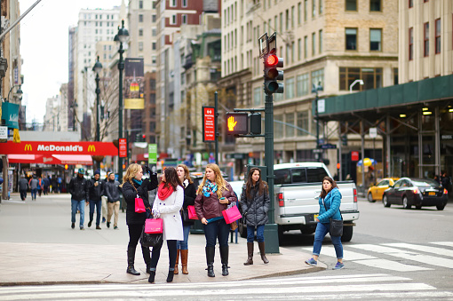 New York - March  16, 2015: People crossing a street in downtown Manhattan. Tourists and new yorkers walking across a busy NYC crosswalk.