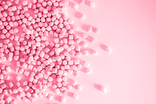 Color of year 2023 Viva Magenta. Image with small round marshmallows is toned in Color Institute color of viva magenta. New Fashion colour. Pile of twisted marshmallows. Side view. Sweets