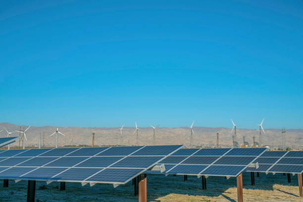 istock Solar panels with windmills blue sky and mountain in the background 1446613000