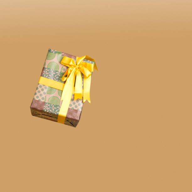 Closeup Of Wrapped Christmas and New Year Gift in Yellow Paper Tiny Box Placed Over Yellow Background. Horizontal Image