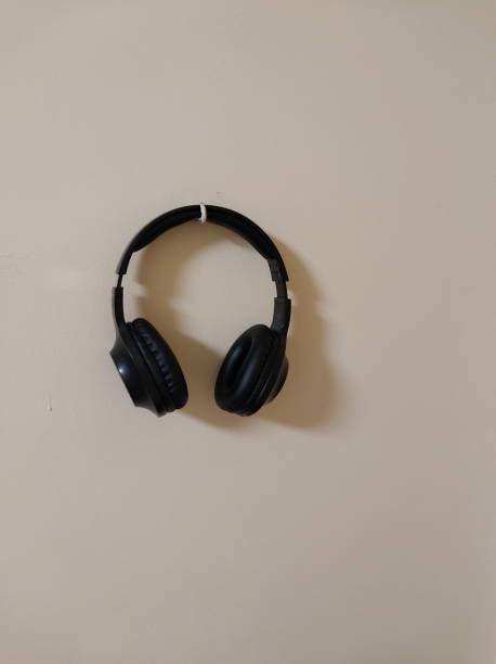 Hanging wireless black headphones on the wall stock photo