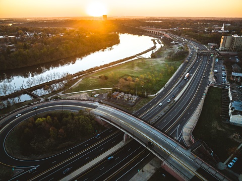 A drone view of a city skyline with highways and buildings near the river at sunrise in New Brunswick, Rutgers, Hub City, USA