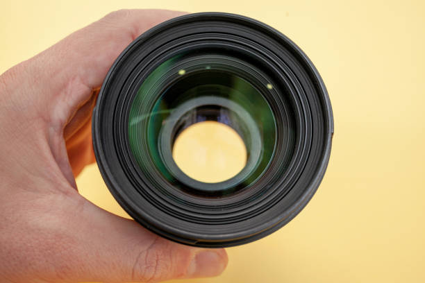 close-up de um homem segurando uma lente de câmera na mão em um fundo - photography lens aperture sharp - fotografias e filmes do acervo