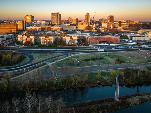 A drone view of a city skyline with buildings illuminated by sun rays near the river at sunrise in New Brunswick, Rutgers, Hub City, USA