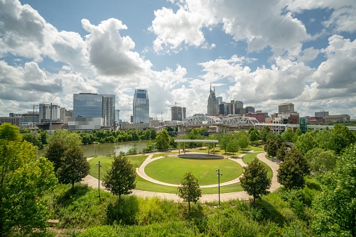 A green park and the city skyline of Nashville under a cloudy sky in Tennessee, USA