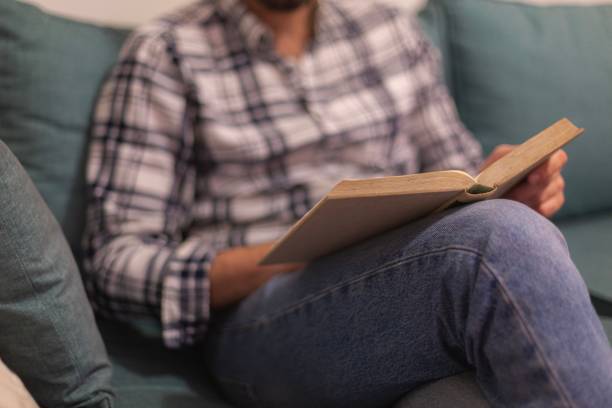 istock Caucasian man sitting on a sofa and reading a book. 1446620913