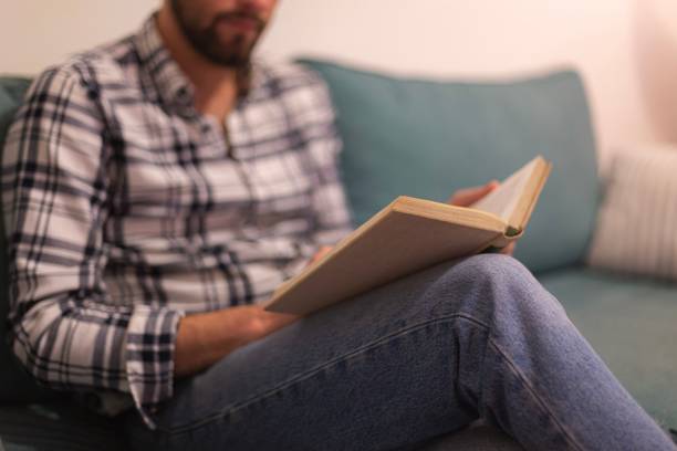 istock Caucasian man sitting on a sofa and reading a book. 1446620915