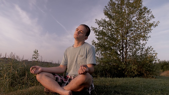 A Caucasian young male practicing yoga outdoors