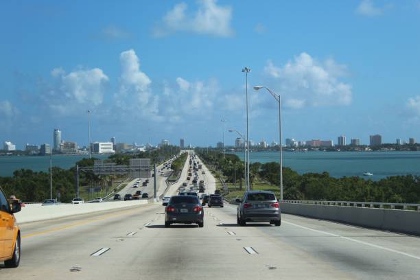 Transport on the highway towards Miami, sunny sky, clouds in the distance Miami, United States – November 04, 2018: The transport on the highway towards Miami, sunny sky, clouds in the distance miami marathon stock pictures, royalty-free photos & images