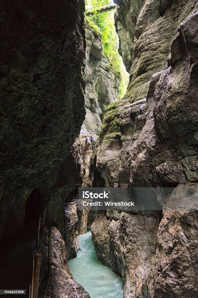 Vertical of the Partnachklamm canyon and a thin river flowing in the middle, Germany A vertical of the Partnachklamm canyon and a thin river flowing in the middle, Germany Blue Stock Photo