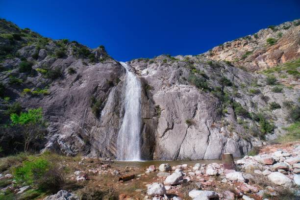 istock Beautiful waterfall streaming down to a small pond 1446622704