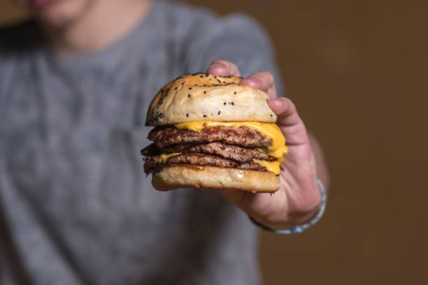 istock Closeup of a cheeseburger held by a man 1446624213