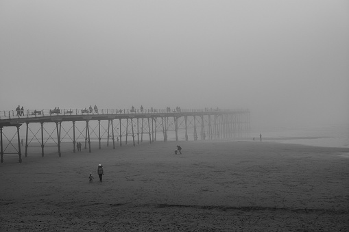 People crossing the bridge at Saltburn beach in a foggy weather