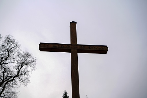 A low-angle view of a wooden cross against a cloudy sky
