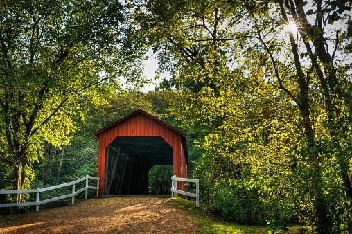 red covered bridge across stream with early autumn color, in Missouri