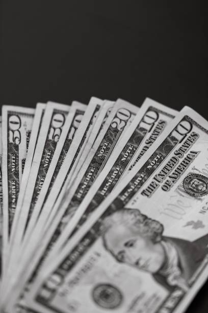istock Vertical grayscale closeup of dollar banknotes on dark background. 1446627623