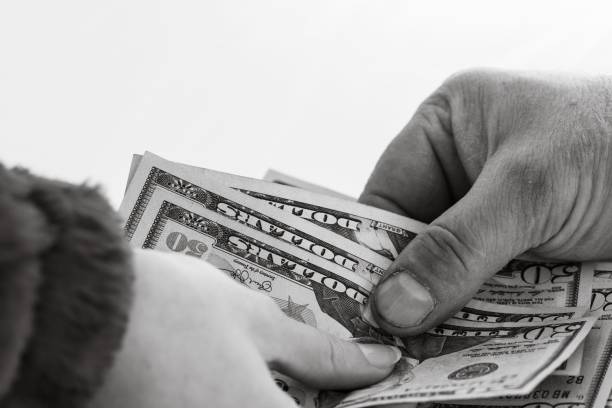istock Grayscale closeup of hands exchanging money. 1446627651