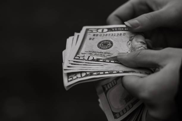 istock Grayscale closeup of hands counting money. 1446627677