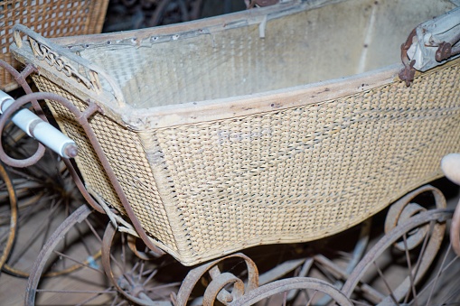 An old and dirty wicker stroller in a garage