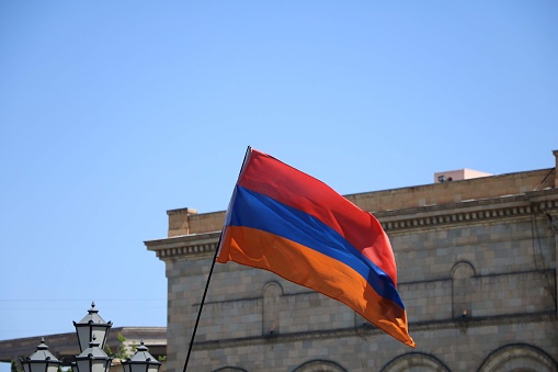 Bandera de Armenia ondeando con el edificio de la Plaza de la República al fondo photo