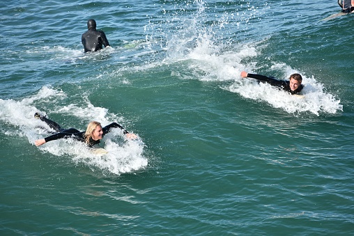 San Diego, United States – November 05, 2022: The aerial view of people surfing in the Pacific Ocean under the sunlight