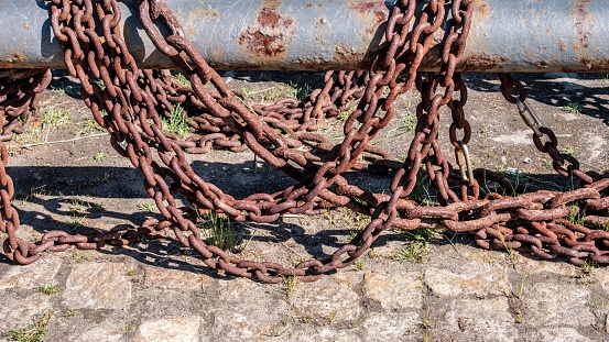 A closeup of old rusty chain on a metallic pipe