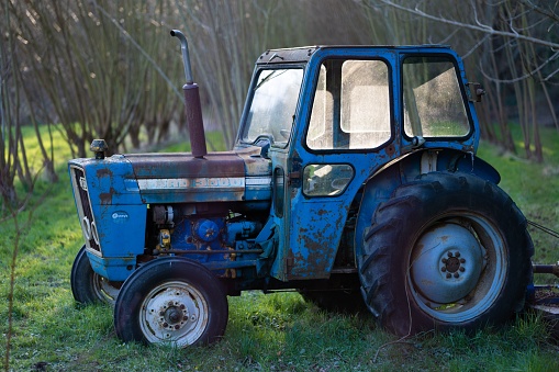 An old blue tractor with its big wheels on the field