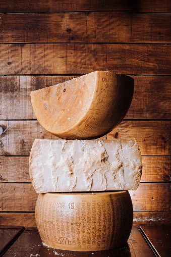 A vertical shot of a stack of delicious parmesan cheese wheels on a wooden table