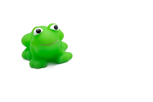 A closeup shot of a smiling green plastic toy frog isolated on a white background
