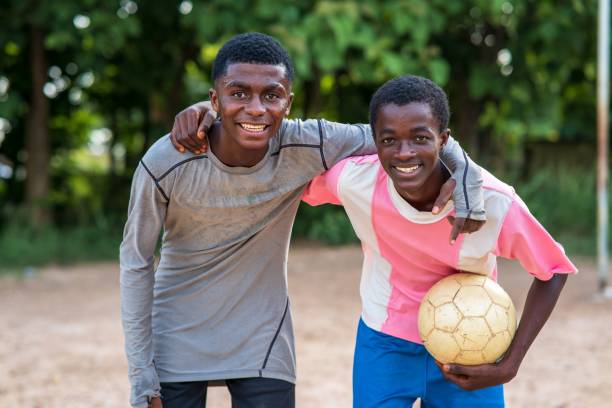 istock Young African boys smiling at the camera with arms around each other's shoulder while playing soccer 1446635893