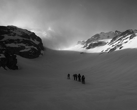 The grayscale shot of a group of people skiing on the snow-covered mountains of Entremont