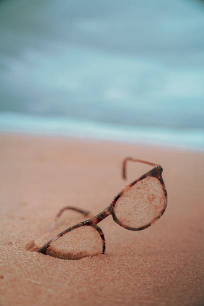 istock Closeup shot of glasses on a sandy beach 1446636731