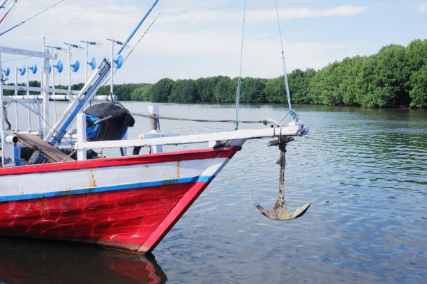 the front side of a large fishing boat moored in the harbor. anchor hanging, seen from below stock photo