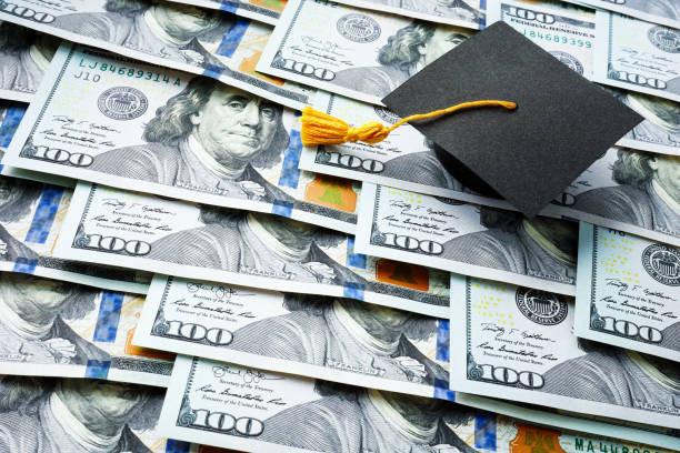 Graduation cap on the stack of money. Student loan concept. stock photo