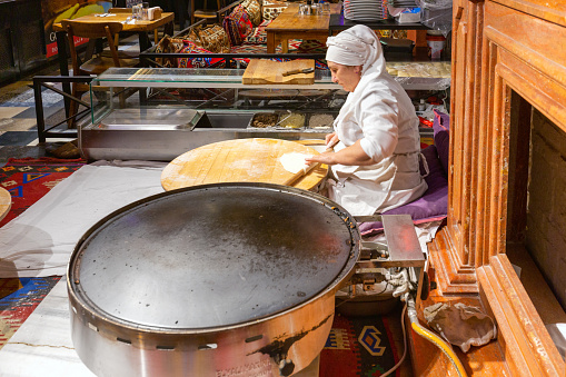 Istanbul, Turkey - May 19, 2022: An elderly woman makes pancakes in the restaurant
