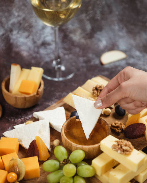 istock Dipping cheese into honey. Platter, snacks and white wine. Overhead 1446648824
