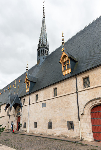side view of the exterior and the spire of the famous Hôtel-Dieu, the building of the former hospital now belongs to the hospices civils de Beaune and is a museum. The city of Beaune lies in the heart of the French wine-growing region of Burgundy, the city is surrounded by the vineyards of the Côte d'Or. 01/06/2022 - 2 Rue de l'Hôtel Dieu, 21200 Beaune, France