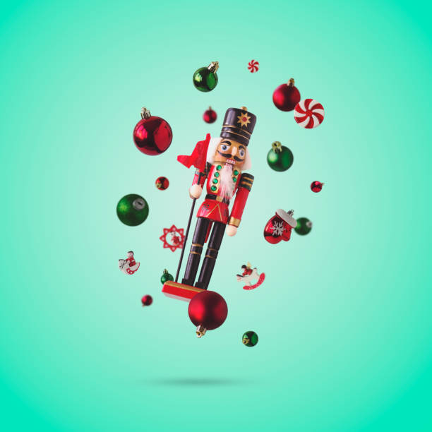 Nutcracker and Christmas baubles on green background, levitating. Christmas and New Year creative concept