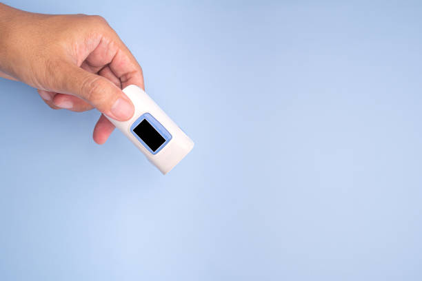 istock Hand holding of a pulse oximeter on a light blue background 1446669943