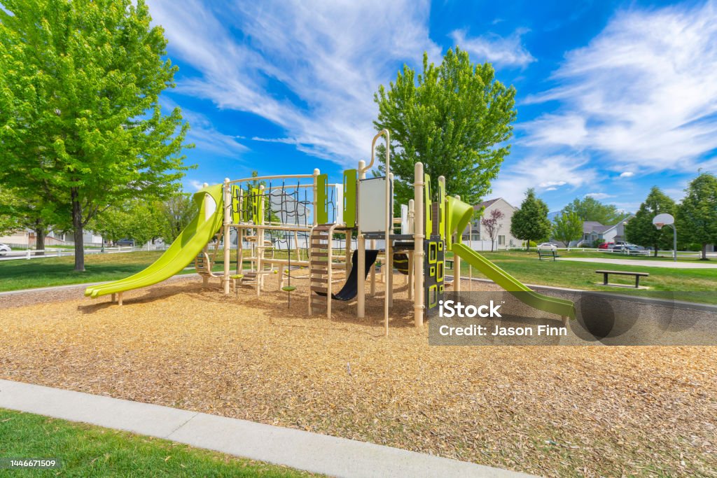 Playground set in a residential community at Utah valley Playground set in a residential community at Utah valley. Playground in a public park with concrete path and basketball court at the back with benches on the side against the houses. Playground Stock Photo